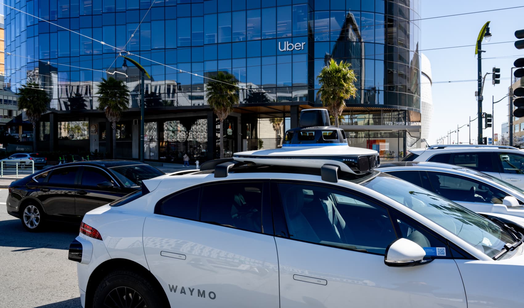 Self-driving Waymo vehicle driving past the headquarters of Uber, with signage visible, in the Mission Bay neighborhood, San Francisco, California, March 18, 2025.